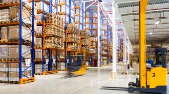 Warehouse with machinery and shelves full of boxes and palettes.